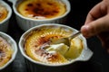 hand using a spoon to crack the top of a creme brulee