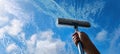 The hand using a squeegee to clean a window against a bright sky AI generated image Royalty Free Stock Photo