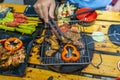 Hand holding tongs and grilling marinated meat and bell peppers Royalty Free Stock Photo