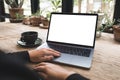 Hand using and typing on laptop with blank white desktop screen on vintage wooden table in cafe Royalty Free Stock Photo