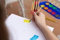 Hand view from above of teenage girl holding a brush, painting with watercolors a chromatic circle outdoors. Royalty Free Stock Photo