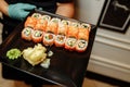 Hand Waiter holding Set Delicious fresh Sushi slate plate, Japanese raw fish in traditional restaurant. Philadelphia