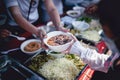 The hand of the wanderer extends to receive food from donations. With volunteers scooping food: the idea of helping with hunger