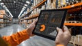 the hand of a warehouse worker operates a tablet, managing a digital construction system with a dashboard, against the Royalty Free Stock Photo