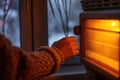 Hand warms up near an electric heater. Winter cold and expensive gas prices, energy crisis. Generative AI Royalty Free Stock Photo