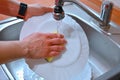 Hand washing dishes. Hand with sponge and sink in kitchen washing dirty dishes - plate Royalty Free Stock Photo