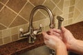 Hand washing under water flowing out a faucet