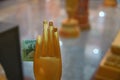 In hand wax statue a Buddhist monk inserted donation banknote. Concept of religious donations alms in Buddhist temple.