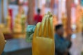 In hand of the wax statue of a Buddhist monk inserted donation banknote. Concept of religious donations alms in Buddhist temple.