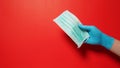 Hand wear glove and holding face Mask on red background