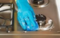 Hand wearing rubber glove while cleaning stove top range with s