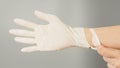 Hand wearing white torn gloves on grey background