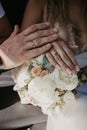 A hand of wedding couple touch each other over wedding bouquet. Hands newlyweds with wedding rings close up. Bridal hands with Royalty Free Stock Photo