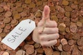 The hand which is sticking out of heap of coins with sales tag.Copy space Royalty Free Stock Photo