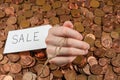 The hand which is sticking out of heap of coins with sales tag.Copy space Royalty Free Stock Photo