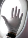 Hand in a white glove on the background of the window in the plane