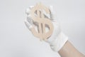 Hand in White Glove holds wooden Dollar Sign