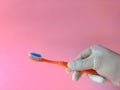 Hand with white latex glove holding a toothbrush on pink background. medical concept Royalty Free Stock Photo