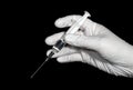 A hand in a white latex glove holds a syringe