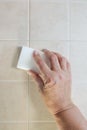 hand with a white melamine sponge washes the tile