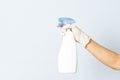 Hand with white nitrile glove holding cleaning spray on white background