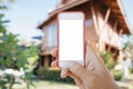 Hand white phone mockup on summer house background. Investments and an application for choosing real estate Royalty Free Stock Photo