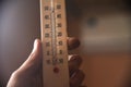 Hand with a white plastic mercury thermometer shows the temperature in the room Royalty Free Stock Photo