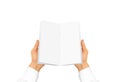 Hand in white shirt sleeve holding blank brochure booklet in the