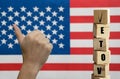 A hand with a white skin color, with the finger raised up, next to the word voice in front of the defocused American flag. The Royalty Free Stock Photo