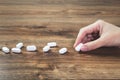 Hand with white tablets on wooden table. Medicine Royalty Free Stock Photo