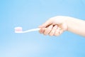 Hand with white toothbrush with toothpaste on blue background. H Royalty Free Stock Photo