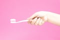 Hand with white toothbrush with toothpaste on pink background. H Royalty Free Stock Photo