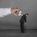 Hand windering winder on businessman's back, concrete background