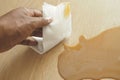 hand wiping spilled tea with paper napkin on floor , Royalty Free Stock Photo