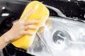 Hand woman car wash foam with yellow sponge headlights Royalty Free Stock Photo
