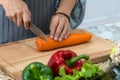 hand woman carrot with kitchen knife on cutting board. Chef cuts the vegetables into a meal Royalty Free Stock Photo