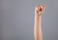 Hand of woman with clenched fist on gray background