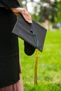 Graduate Wearing Gown and holding Motarboard In Park