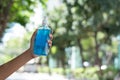 Hand of woman hold blue sanitizer alcohol hand gel for protecting coronavirus, background is blur bokeh of the trees, COVID-19