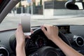 Hand of woman holding steering wheel and mobile phone driving car while texting distracted in risk Royalty Free Stock Photo