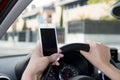 Hand of woman holding steering wheel and mobile phone driving car while texting distracted in risk Royalty Free Stock Photo