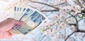 hand woman with Japanese currency yen bank notes on sakura cherry blossom tree in Gongendo park Japan, travel cost concept Royalty Free Stock Photo