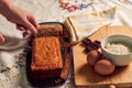 Hand of a woman with a knife cuts a sponge cake with some ingredients on a white tablecloth Royalty Free Stock Photo