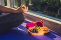 Hand of a woman meditating in a yoga pose, sitting in lotus with fruits in front of her dragon fruit, mango and mulberry