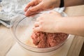 Hand of woman mixing mixed minced meat of pork and beef with ground spices in bowl on cutting board for cooking in domestic