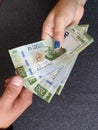 hand of a woman paying with Mexican money and hand of a man receiving