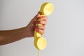 Hand of a woman with red nails holding a yellow retro old-fashioned phone handset on white background Royalty Free Stock Photo