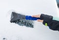 Hand of a woman Scraping snow and ice from the car windscreen