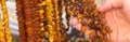 Hand of woman with shiny womanly amber necklaces on stall at bazaar