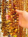 Hand of woman with shiny womanly amber necklaces on stall at the bazaar